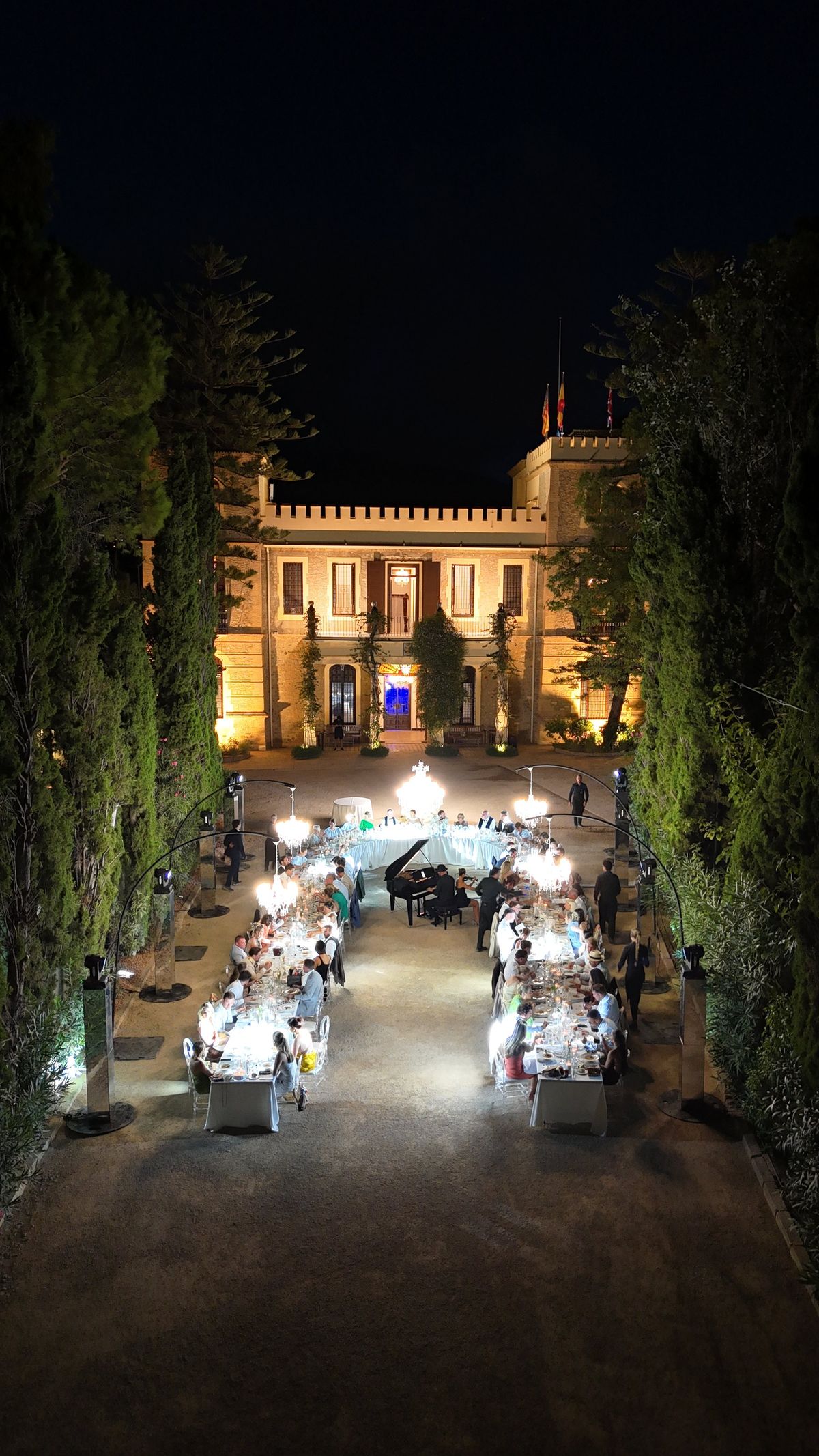 Night aerial of a lit estate with an event set out along the front drive