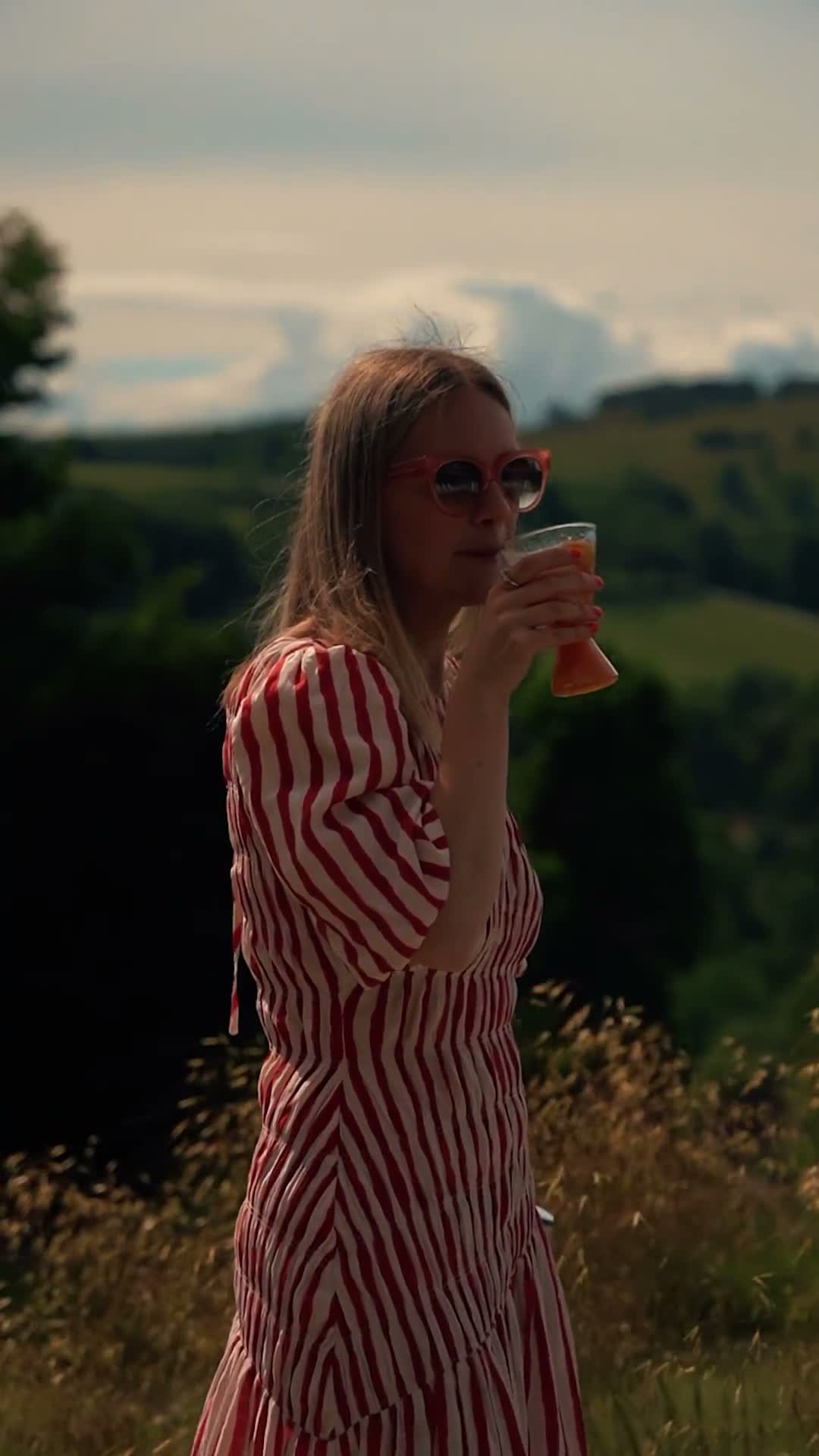 A woman in a striped dress walking through a summer field with a can of Clean Co